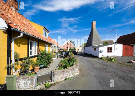 Kleine bunte Fachwerkhäuser in Aarsdale, Bornholm, Dänemark. Schornstein der traditionellen Räucherei im Hintergrund Stockfoto