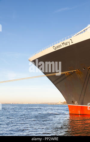 Cunard Cruise Liner Queen Mary 2 ist dargestellt in Brooklyn, New York angedockt. Die Freiheitsstatue kann im Hintergrund gesehen werden. Stockfoto