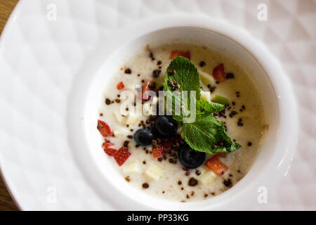 Guten Morgen, Frühstück und gesunde Ernährung Konzept - Lecker brei Haferflocken mit Erdbeeren, Minze, Blaubeeren und Schokolade in weiße Schüssel plat Stockfoto