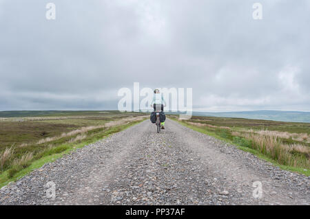 Weibliche Radfahrer in Northumberland moorland Reisen auf der britischen Küste zu Küste Radweg Stockfoto