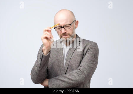 Kahlen reifen europäischen Mann denkt an etwas mit Bleistift. Wie dieses Problem zu lösen Stockfoto