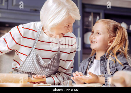 Hübsches Mädchen lächelnd ihre Oma während Cookies mit ihr machen Stockfoto