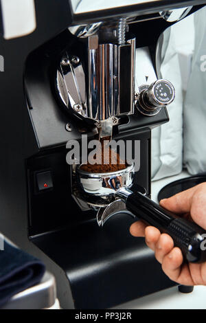 Frisch gemahlenen Kaffeebohnen in einem portafilter durch die Kaffeemühle Stockfoto