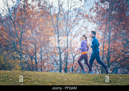 Frau und Mann Joggen oder Laufen im Park im Herbst Stockfoto