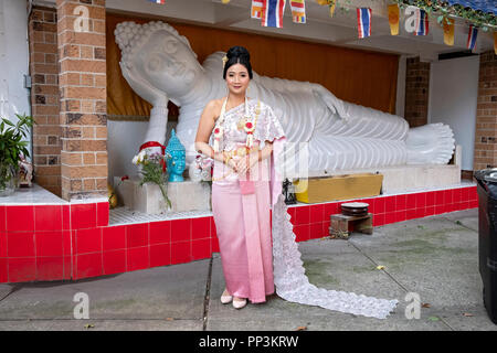 Porträt einer schönen thailändischen buddhistischen Braut nur nach ihrem Jäten vor einer Statue von Buddah. In Elmhurst, Queens, New York City, Stockfoto