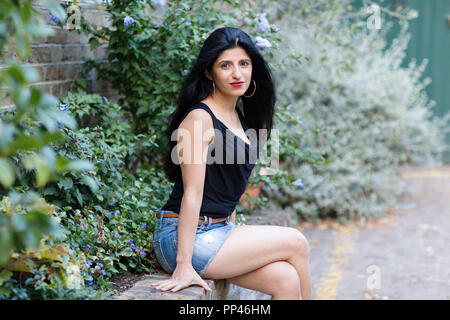 Schönen indischen Frau sitzt an einer Wand Stockfoto