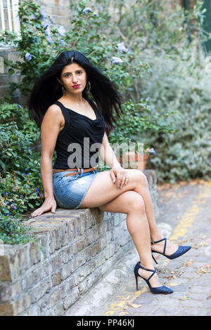 Schönen indischen Frau sitzt an der Wand. Stockfoto