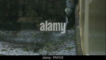 Wasserstrahl aus Rohr bei starkem Regen mit Hagel, breite Foto Stockfoto