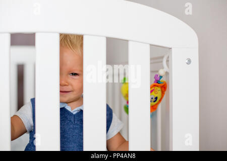 Trauriges kleines Baby Boy, schön gekleidet, Gefühl im Babybett unglücklich, Bars Stockfoto