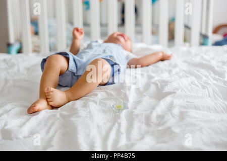 Kleinkind baby boy, spielen mit Dummy, Weinen unglücklich für die Schnuller im Kinderzimmer Stockfoto