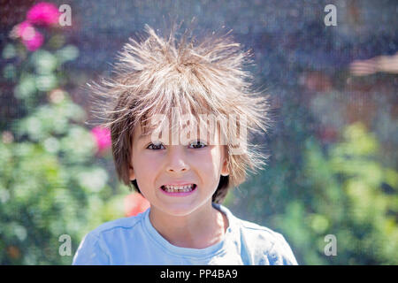 Süße kleine Jungen mit statischen electricy Haar, in seiner komischen Porträt im Freien auf einem Trampolin genommen Stockfoto