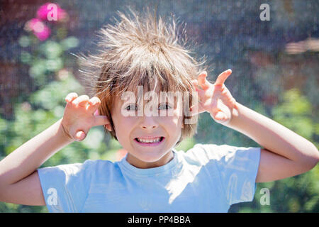 Süße kleine Jungen mit statischen electricy Haar, in seiner komischen Porträt im Freien auf einem Trampolin genommen Stockfoto