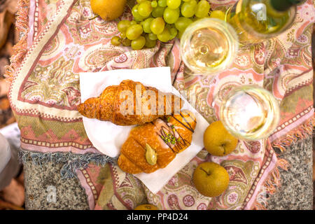 Zwei Gläser Weißwein und Croissants auf den Tisch. Romantik und Blätter im Herbst. Ansicht von oben. Kopieren Sie Platz. Stockfoto