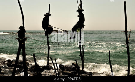 Silhouetten der traditionellen Fischer bei Sonnenuntergang in der Nähe von Galle in Sri Lanka. Stockfoto