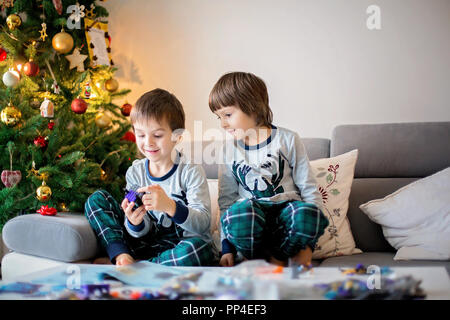 Vorschule Kinder, junge Brüder, Spielen zusammen mit bunten Blöcken, Gebäude verschiedene Spielzeuge am Weihnachtstag, nach der Eröffnung präsentiert auf der Startseite Stockfoto