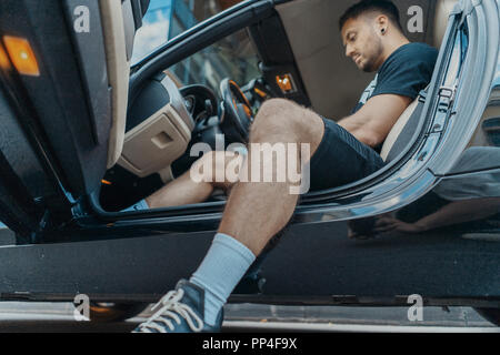 Nahaufnahme von jungen attraktiven Mann hinter dem Rad des schwarzen Auto sitzen. Stockfoto