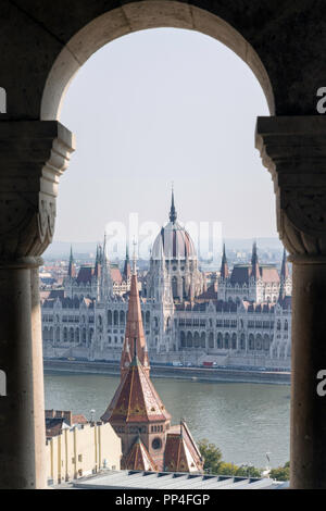 Das ungarische Parlament Gebäude durch den Bögen der Fischerbastei auf dem Burgberg von Budapest gesehen Stockfoto