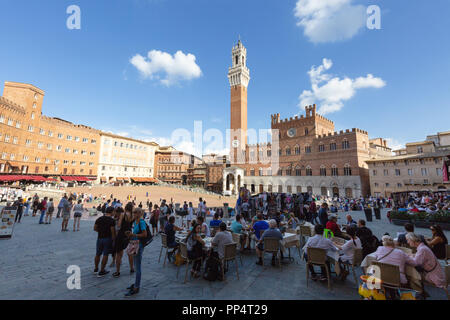 Touristen in einem Café auf der Piazza Del Campo mit dem Palazzo Pubblico und Torre del Mangia, Siena Italien Europa Stockfoto