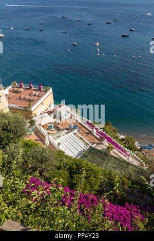 Positano durch rosafarbene Bougainvillea und Boote im Hintergrund eingerahmt. Bunte Positano, das Juwel der Amalfi Küste, mit seinen bunten Häusern und Stockfoto