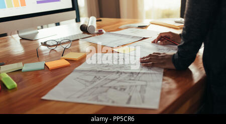 Close up od Frau Designer mit Haus plan an Ihrem Schreibtisch arbeiten. Hände von kreativen weiblichen Interior Designer arbeiten Gehäuse plan auf dem Tisch. Stockfoto