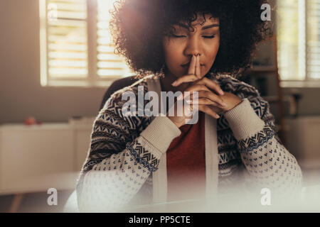 Afrikanische Frauen sitzen an Ihrem Schreibtisch und denken mit geschlossenen Augen. Betonte Frau eine Pause mit Lösung mit Achtsamkeit zu kommen. Stockfoto