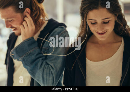 Glückliches Paar Hören von Musik im Kopfhörer. Schüchterne Frau, die mit ihrem Freund zusammen Musik hören. Stockfoto