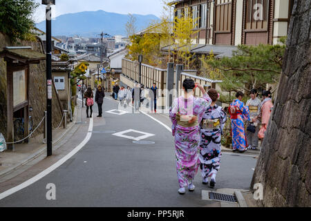 KYOTO, Japan - 08 Feb 2018: Bunte junge japanische Mädchen in traditionellen Kimonos gekleidet gehen hinunter eine Straße in Gion Stockfoto