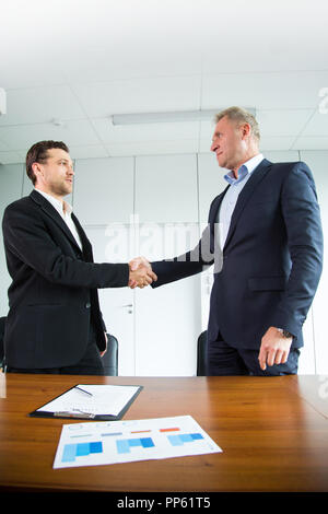 Geschäftsleute Handshake, Geschäftsleute die Hand schütteln, während der Sitzung unterzeichnen Vereinbarung Vertrag standuing am Schreibtisch, Diagramm, Grafik, business Cha Stockfoto