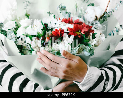 Blume Anordnung gegen den weißen Hintergrund Nahaufnahme Frau hält einen großen Blumenstrauß in einem Papier, das Paket in den Händen Stockfoto