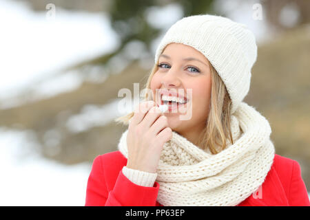 Glückliche Frau Anwendung Lippenbalsam im Freien im Winter in der verschneiten Berg Stockfoto