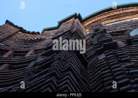 Hintergrund von gekrümmten alten Orange brick wall mit blauem Himmel und Sonne Licht im Hintergrund. Keine Menschen. Stockfoto