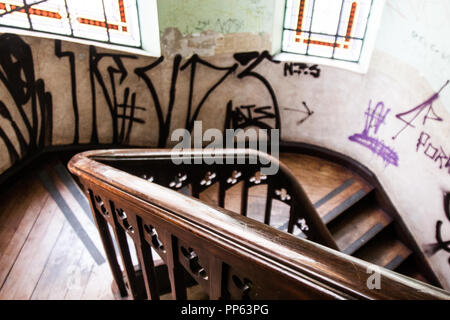 Hintergrund von Kohle, Holz Treppen eines verlassenen Vintage House mit Graffiti an den Wänden und Buntglasfenstern. Keine Menschen. Stockfoto