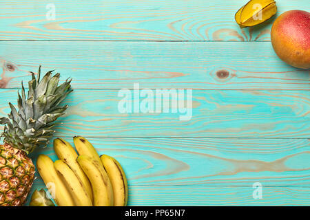 Mango, Karambolen, Banane, Ananas auf einem blauen Hintergrund aus Holz mit kopieren. Tropische Früchte. Flach Stockfoto