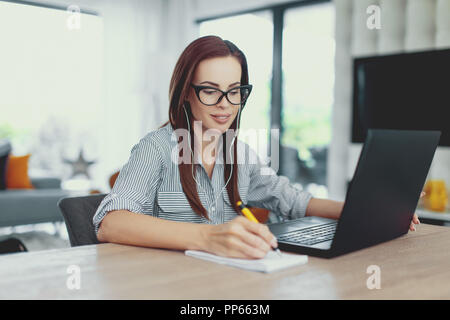 Sorgfältige nerd Studentin Frau Notizen am Laptop, im Innenbereich Stockfoto