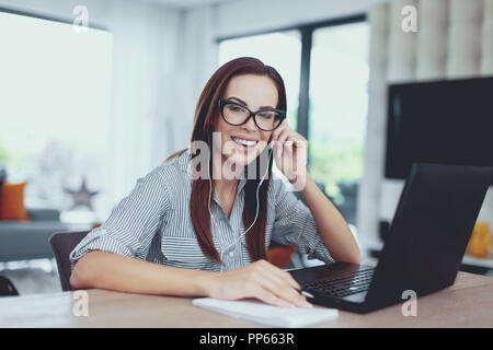 Glückliche junge Nerd kaukasische Frau lernen auf Prüfungen im Innenbereich Stockfoto