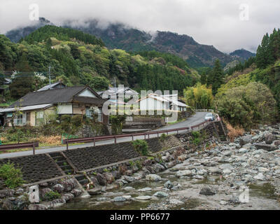 Häuser in Bergdorf, Straße neben klares Wasser mountain river, Wolken auf Forest Hills Kobaru, Kyushu, Japan Frühjahr 2018 Stockfoto