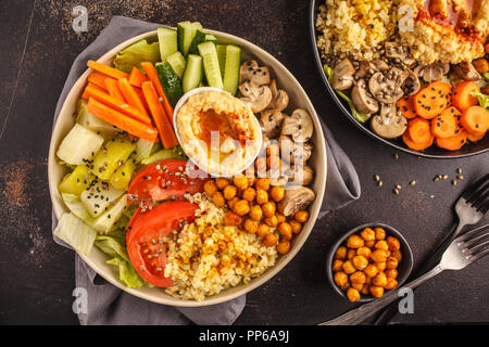 Buddha Schüsseln mit Gemüse, Pilzen, Bulgur, Hummus und gebackene Kichererbsen. Dunkler Hintergrund, Ansicht von oben. Gesunde vegane Ernährung Konzept. Stockfoto