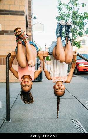 Glücklich lächelnde Mädchen hängen von Bike Rack bar auf Bürgersteig Stockfoto