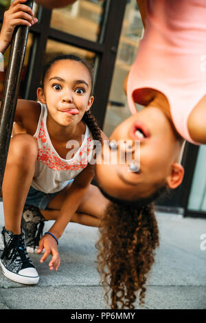 Glücklich lächelnde Mädchen hängen von Bike Rack bar auf Bürgersteig Stockfoto