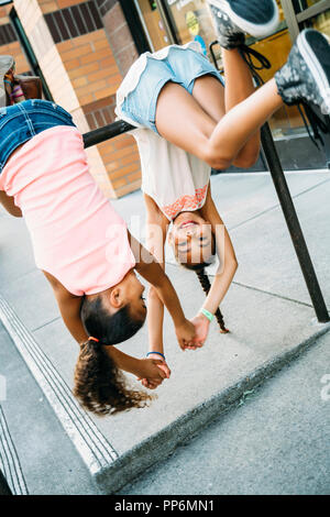 Glücklich lächelnde Mädchen hängen von Bike Rack bar auf Bürgersteig Stockfoto