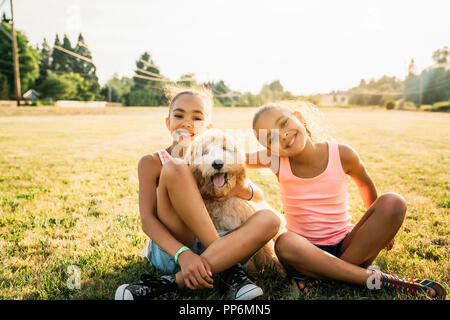 Portrait von lächelnden glückliche Mädchen umarmt labradoodle Welpen in Park Stockfoto