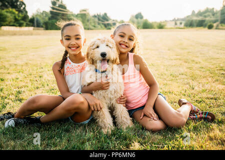 Portrait von lächelnden glückliche Mädchen umarmt labradoodle Welpen in Park Stockfoto