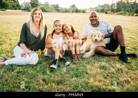 Portrait von Mixed-race Familie im Feld mit labradoodle Welpen Stockfoto