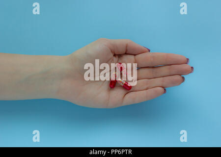 Weibliche Hand hält Pillen auf blauem Hintergrund, Konzept der Gesundheit Stockfoto