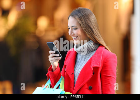 Happy Shopper Shopping und mit einem Smart Phone in einem Einkaufszentrum im Winter Stockfoto