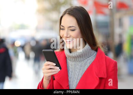 Gerne Frau in Rot Kontrolle telefonische Nachrichten auf der Straße im Winter Stockfoto