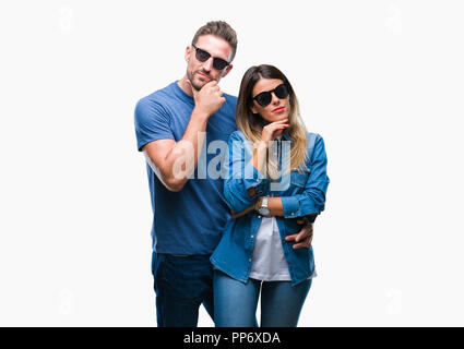 Junges Paar in der Liebe tragen Sonnenbrillen über isolierte Hintergrund mit der Hand am Kinn über die Frage denken, nachdenklichen Ausdruck. Lächelnd mit thoughtfu Stockfoto