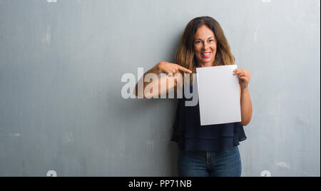 Mittleres Alter Hispanic woman holding Bank Blatt Papier sehr glücklich zeigte mit Hand und Finger Stockfoto