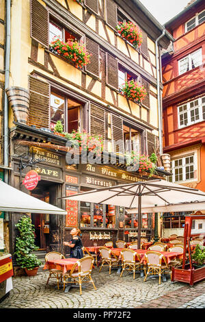 Schönen Gebäuden mit Blumen Blumenkästen an der Au Vieux Cafe mit Essbereich im Freien Tische und Sonnenschirme in Rue du Maroquin, in Straßburg, Frankreich Stockfoto