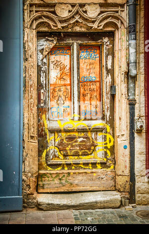 Die vordere Tür Eingang, in französischer Sprache Graffiti bedeckt, auf einem alten, verlassenen baufälligen Gebäude in Straßburg, Frankreich Stockfoto